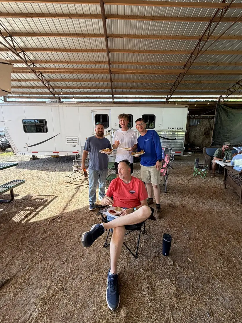 The church's pastor seated in a camp chair with several men of the church standing behind him