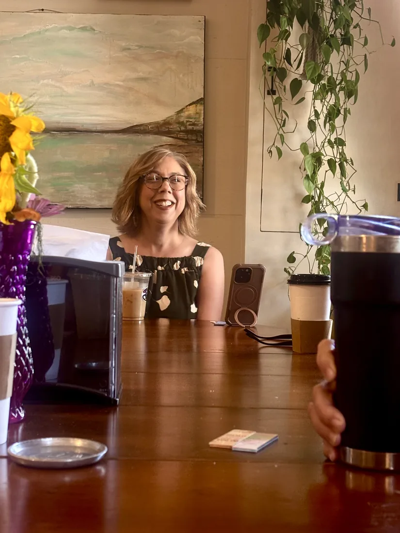 A lady laughing over her iced coffee at the table